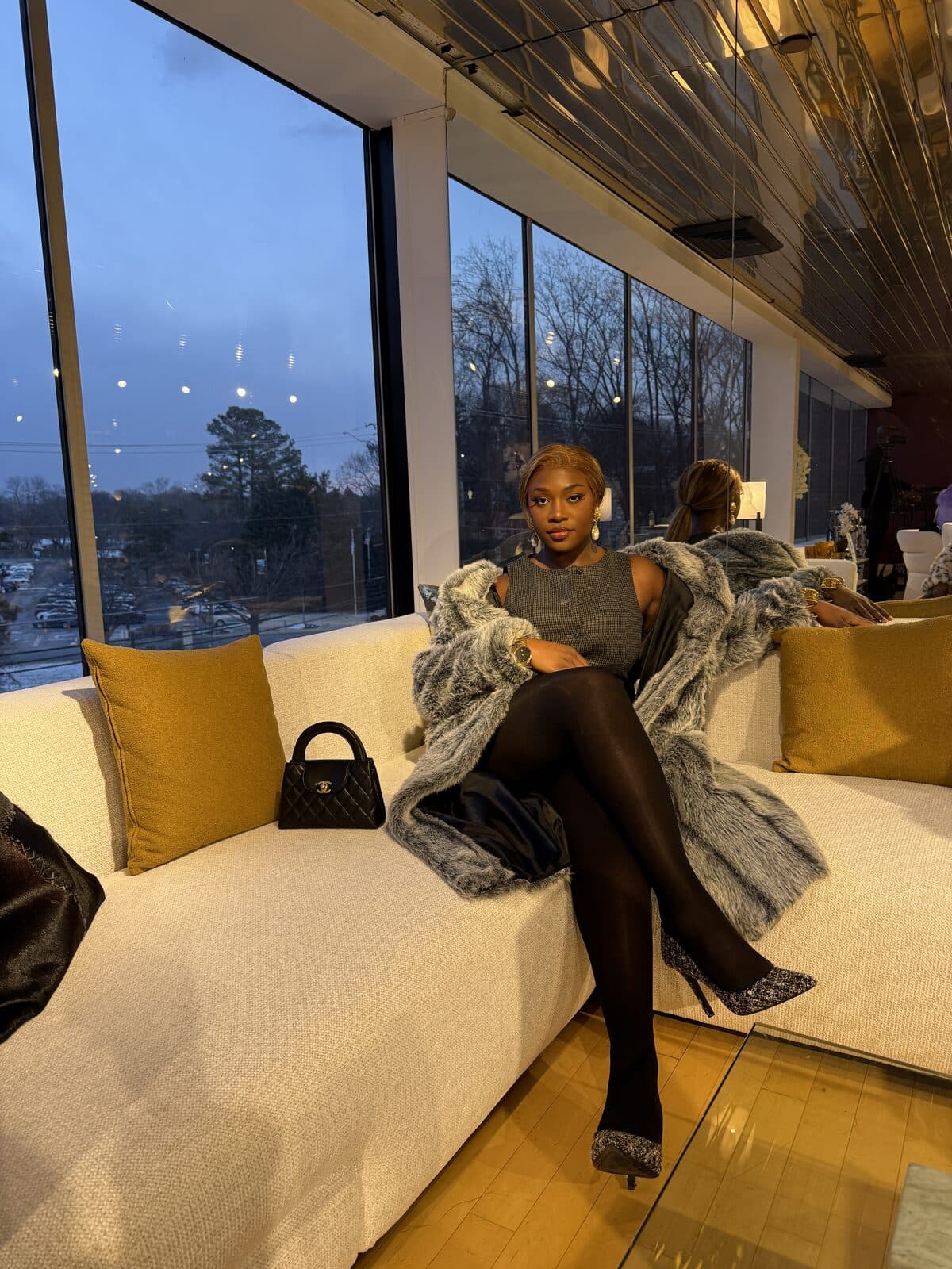 Raissa at dusk on a velvet sofa, draped in a faux-fur coat